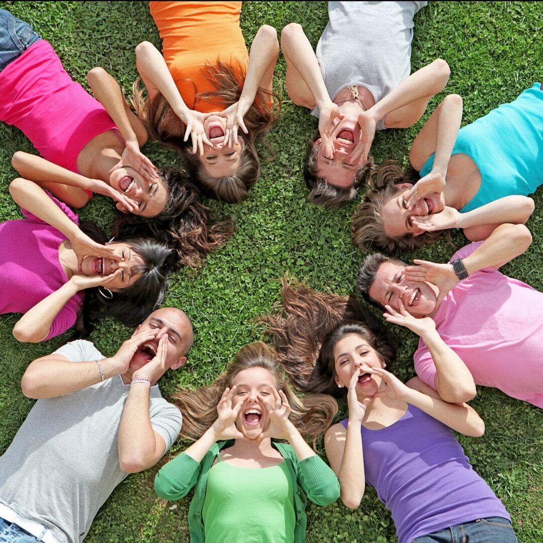 A group of girls laying in the grass with their hands up.